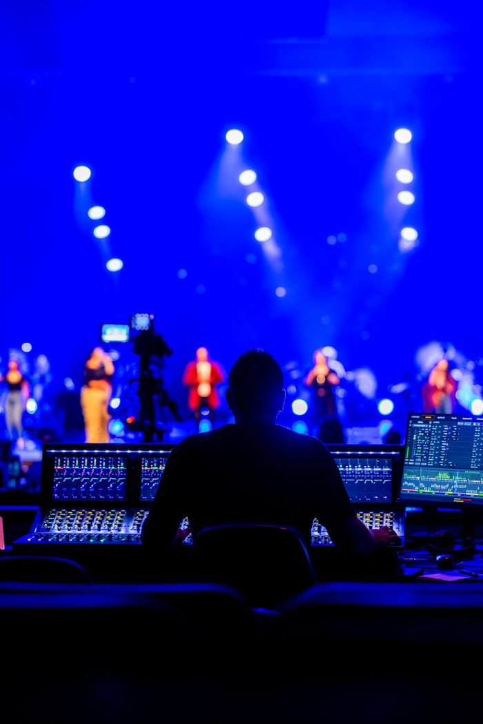 about-us Sound engineer managing live concert with vibrant blue stage lighting.